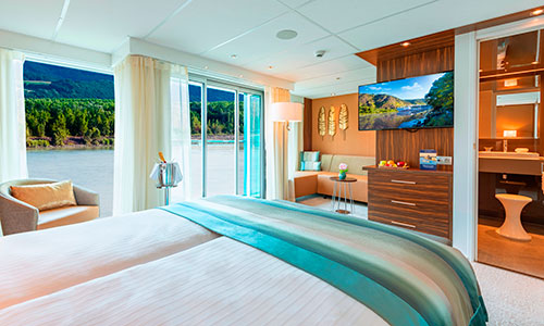 Blick in die Suite mit Schlafbereich und Sitzecke und Balkon auf dem Flusskreuzfahrtschiff Amadeus Star