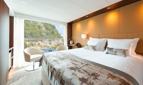 Suite mit Bett und Blick aus dem geöffneten Panoramafenster der Kabine Kategorie A1, B1 und B4 auf dem Flusskreuzfahrtschiff Anadeus Queen