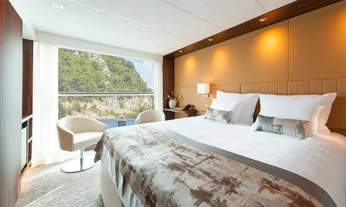 Suite mit Bett und Blick aus dem geöffneten Panoramafenster der Kabine Kategorie A1, B1 und B4 auf dem Flusskreuzfahrtschiff Anadeus Queen