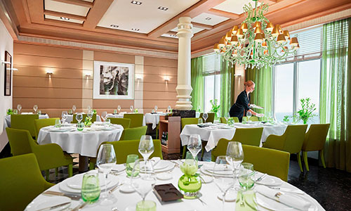 Blick in das Restaurant Serenissima in hellem Flair mit grünen Stühlen