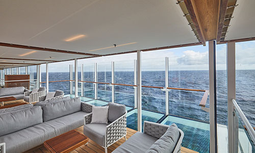 Sitzbereich und Gläserner Balkon mit Blick aufs Meer auf der HANSEATIC inspiration von Hapag-Lloyd