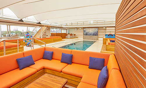 Sitzbereich am Pool mit orangefarbenen Kissen auf dem Luxusexpeditionsschiff HANSEATIC nature der Reederei HL-Cruises