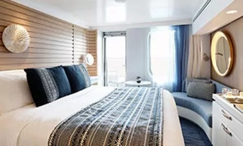 Kingsize Bett und Sitzecke mit Blick auf Balkon auf dem Luxusexpeditionsschiff Le Bougainville der Reederei Ponant