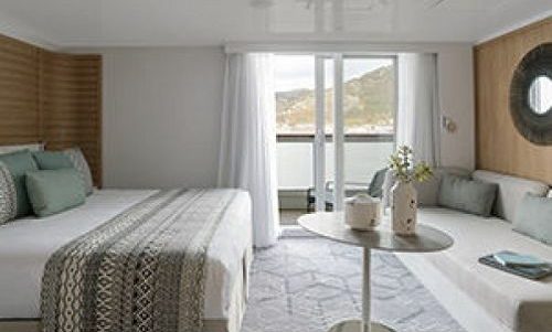 Bett und Sofa mit Blick auf Balkon Deluxe Suite auf dem Luxusexpeditionsschiff Le Bougainville der Reederei Ponant