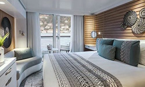 Schlaf- und Sitzbereich Prestige Kabine mit Blick auf Balkon auf dem Luxusexpeditionsschiff Le Bougainville der Reederei Ponant