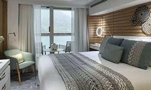Schlaf-und Sitzbereich mit Blick auf Esstisch und Balkon Prestige Suite auf dem Luxusexpeditionsschiff Le Bougainville der Reederei Ponant