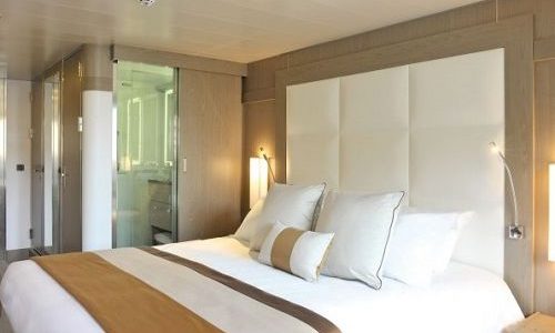 Schlafbereich mit Blick ins Bad in der Deluxe Kabine auf der Luxuskreuzfahrtyacht L'Austral der Reederei Ponant