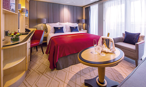 Kingsize Bett Tisch und Sessel und Blick auf Fensterfront in der Princess Grill Suite