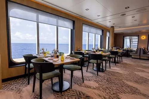 Club Lounge mit gedeckten Tischen vor großen Panoramafenstern