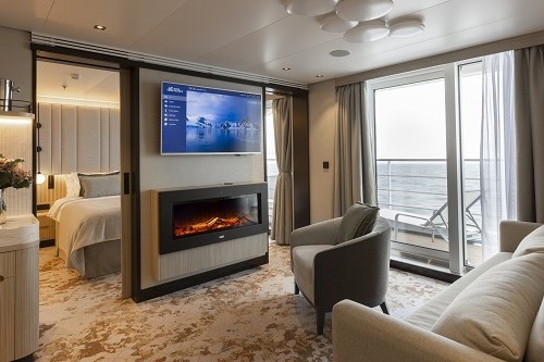 Wohnzimmer Premium Suite mit TV und Kamin und Blick ins Schlafzimmer
