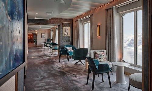 Corridor mit Sitzgelegenheit und Tischen vor grossen Fenstern