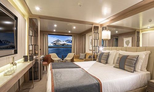 Schlaf- und Wohnbereich mit Blick auf Balkon in der infinitiv Kabine auf dem Expeditionsschiff World Explorer