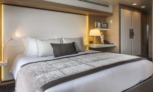 Kingsize-Bett und Kleiderschrank in der Pestige Kabine auf der Luxuskreuzfahrtyacht Le Soleal der Reederei Ponant