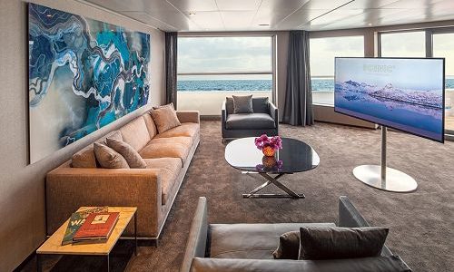 Wohnzimmer mit großem TV und Blick aufs Meer in der Owners Suite auf dem Kreuzfahrtschiff Scenic Eclipse
