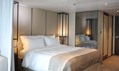 Schlafbereich und Blick auf Bad in Veranda Suite auf dem Kreuzfahrtschiff Scenic Eclipse